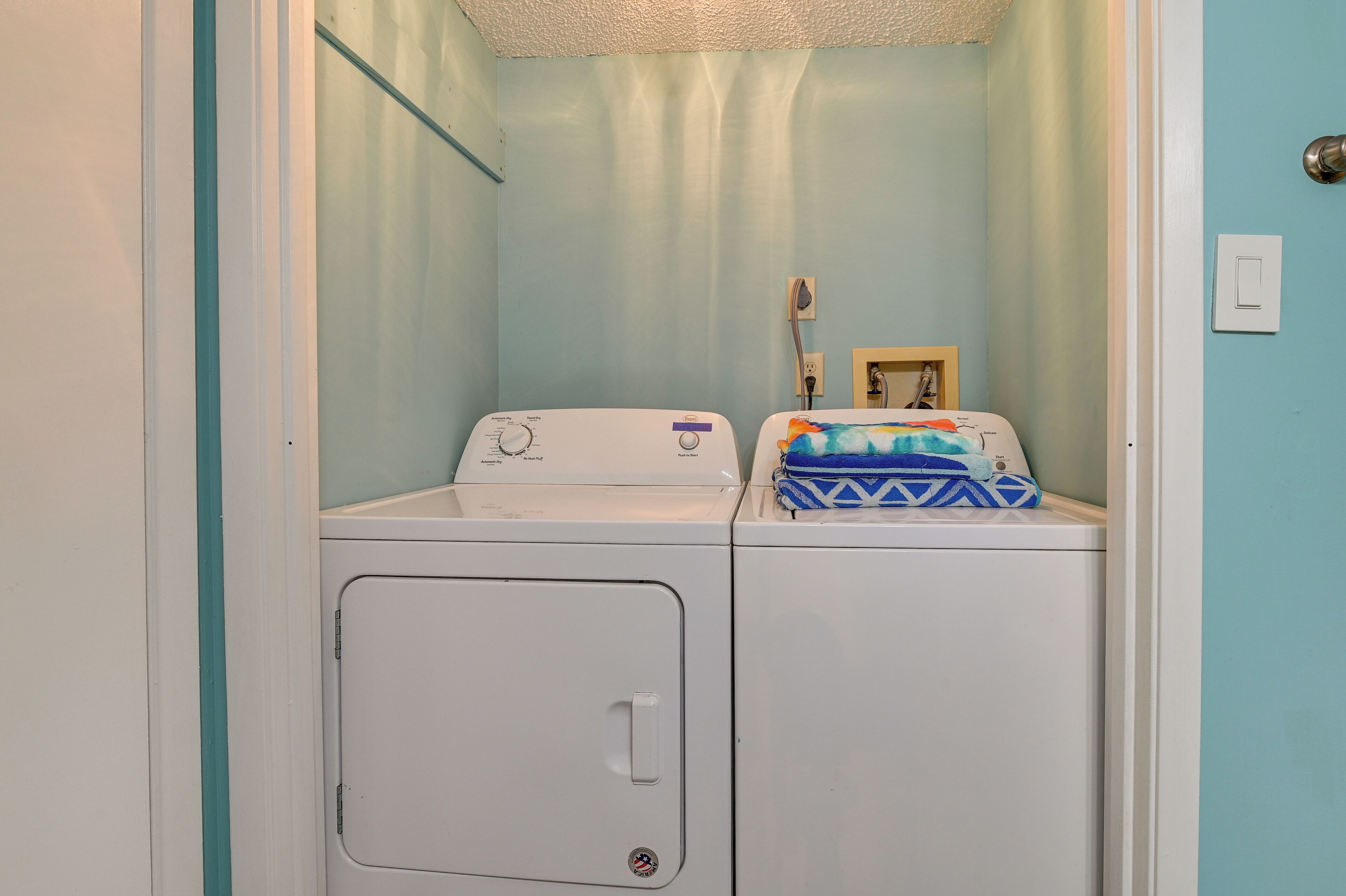 A laundry room with two washing machines, a towel rack, and a small framed picture on the wall.
