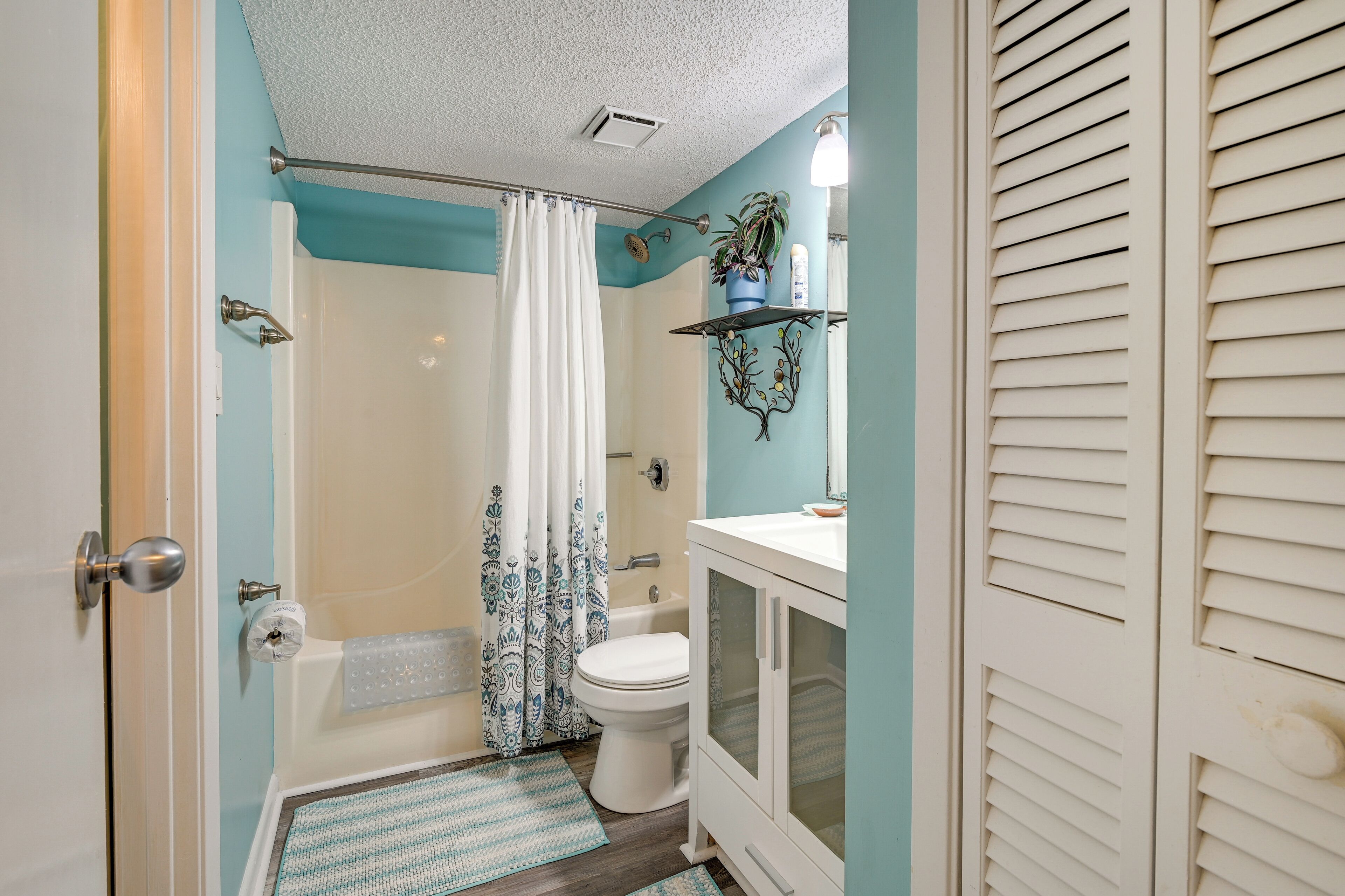 A bathroom with a bathtub, toilet, and shower curtain.