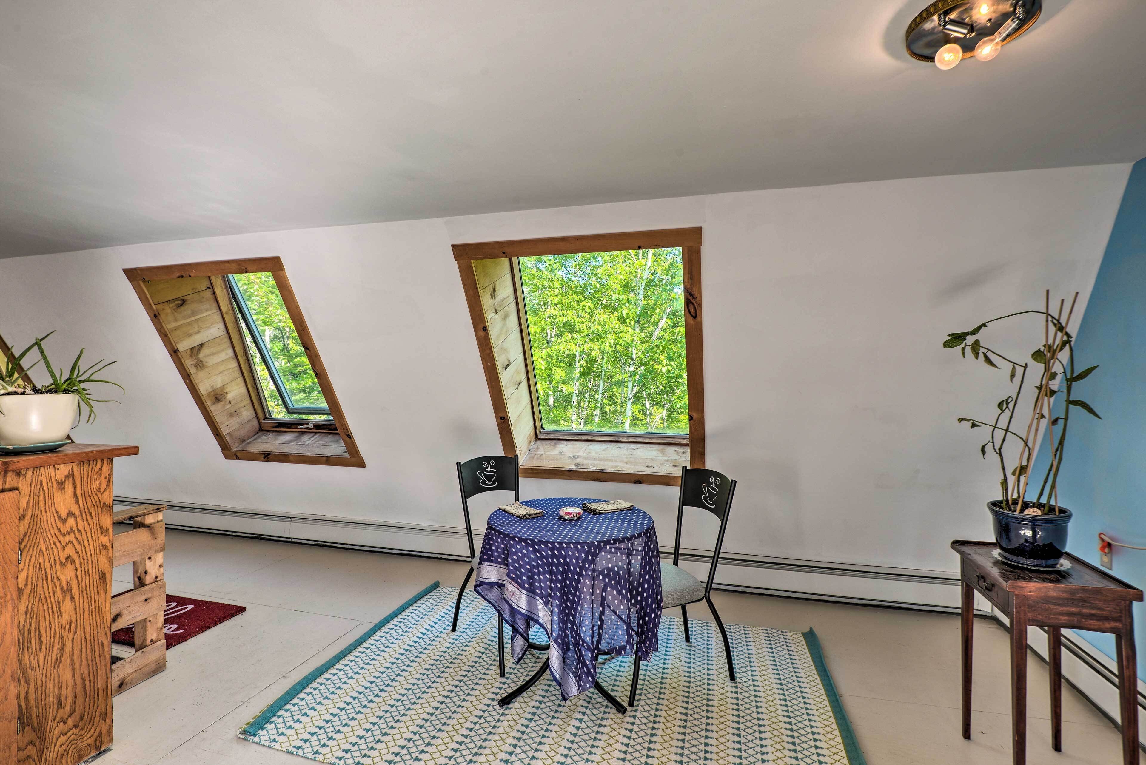 A room with a small table and chairs, a potted plant, and a view through a skylight.