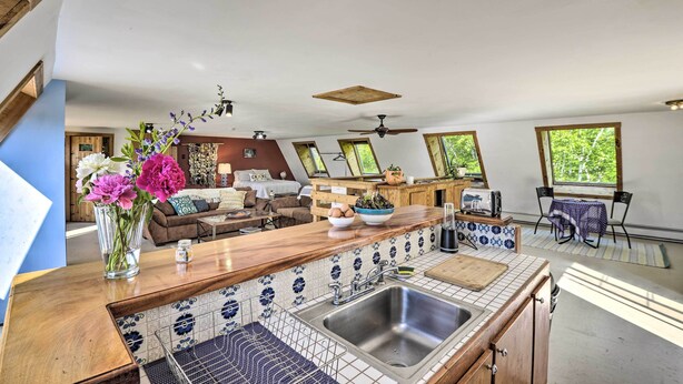 A modern kitchen with a central island, a dining area with a table and chairs, and a living room with a sofa and coffee table. - Charming Studio ~ 20 Mi to Acadia Nat'l Park! (Ellsworth)