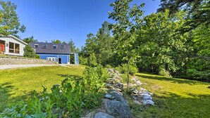 A modern house with a blue exterior, a stone pathway, and a well-maintained garden with various plants and rocks. - Charming Studio ~ 20 Mi to Acadia Nat'l Park! (Ellsworth)