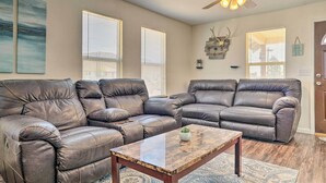 A living room with two brown leather sofas, a wooden coffee table, and a ceiling fan.