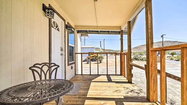 A wooden deck with a table and chairs, a covered porch, and a view of a construction site.