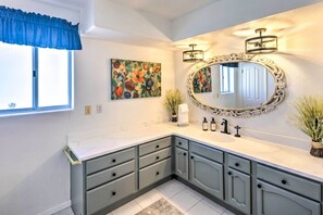 A bathroom with a large vanity, a mirror with an ornate frame, and a floral painting on the wall. - Luxe Home w/ Detached Casita & Furnished Patio! (Bullhead City)