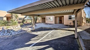 A building with a covered parking area, a small garden, and a clear sky. - Tranquil Green Valley Townhome w/ Mtn Views! (Green Valley)