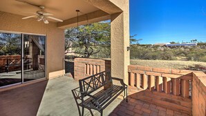 A covered patio with a ceiling fan, a bench, and a glass door leading to an outdoor area with a view of a building and trees. - Tranquil Green Valley Townhome w/ Mtn Views! (Green Valley)