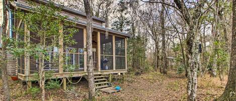 A cabin with a deck, surrounded by trees.