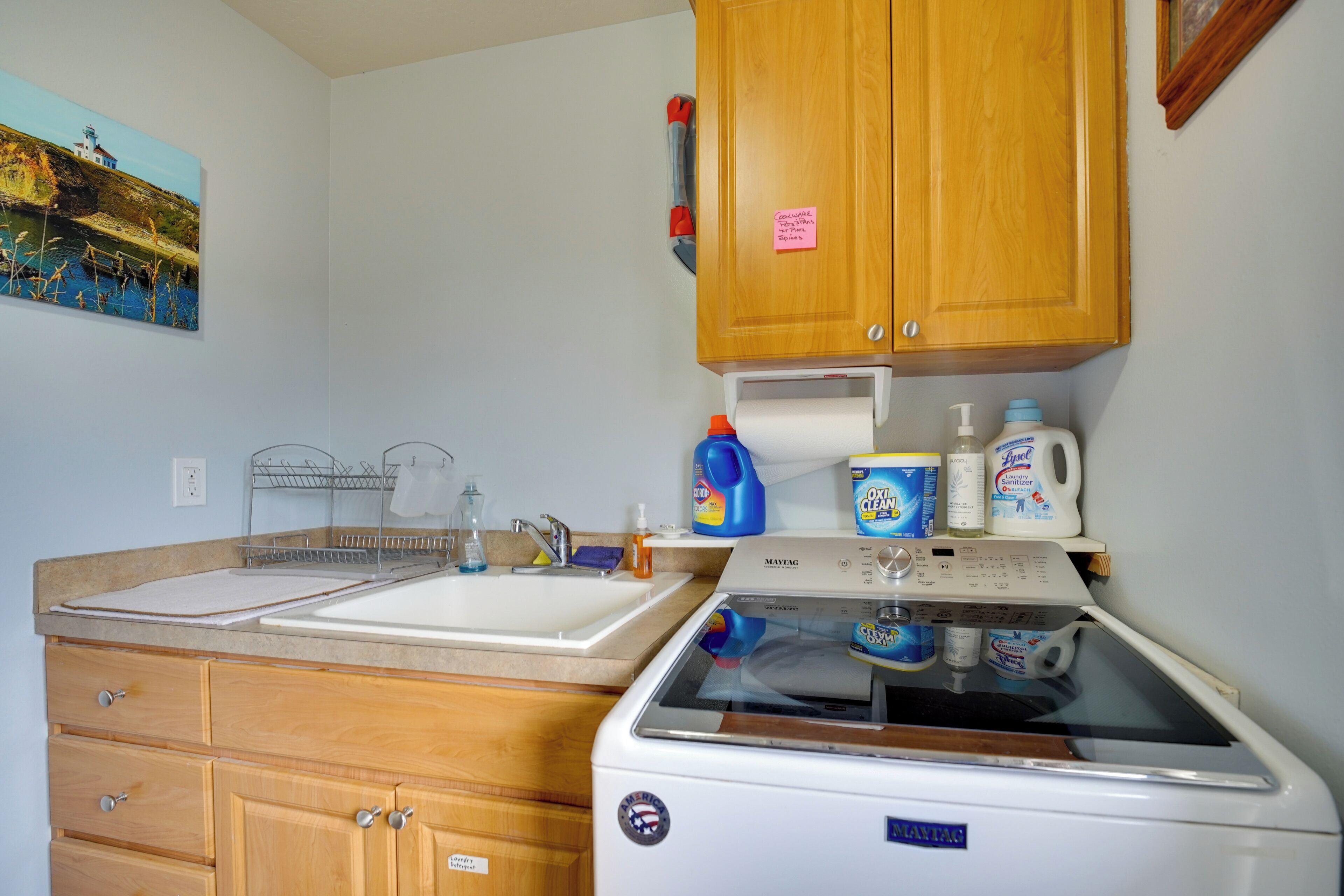 A compact kitchen with a washing machine, a sink, and wooden cabinets.
