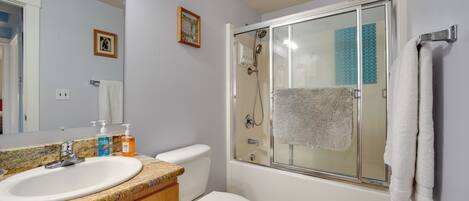 Une salle de bain équipée d’un lavabo, de toilettes et d’une douche à parois de verre.