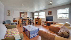 A spacious living room with a dining area, a sofa, a coffee table, and a television. - Springfield Apt w/ Deck + Central Location! (Springfield)