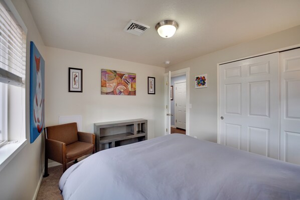 A bedroom with a bed, a chair, a TV stand, and a door. - Springfield Apt w/ Deck + Central Location! (Springfield)