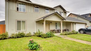 A two-story house with a front porch, a covered patio, and a car parked in the driveway. - Springfield Apt w/ Deck + Central Location! (Springfield)
