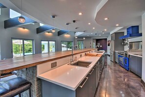 Una cocina moderna con una isla grande, electrodomésticos de acero inoxidable y vistas al exterior.