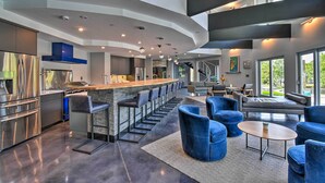 A modern kitchen with a bar area, seating, and a staircase leading to an upper level. - Southern Shores Retreat w/ Expansive Outdoor Space (Kitty Hawk)