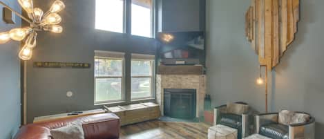 A modern living room with a fireplace, leather sofa, and a unique wooden wall art piece.