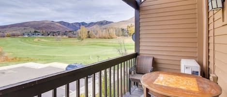 A balcony with a view of a golf course and mountains.