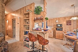 Un intérieur chaleureux en bois, avec un bar, des sièges et une cuisine.