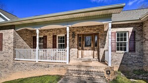 A two-story house with a brick exterior, a front porch with a white railing, and a front door with a glass panel. - Pet-friendly Abingdon Abode w/ Yard & Grill! (Abingdon)