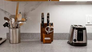 A kitchen counter with a stainless steel utensil holder, a wooden knife block, and a toaster.