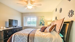 A bedroom with a bed, a dresser, a TV, a ceiling fan, and a window with blinds. - Pool & Hot Tub Access: Modern Palm Springs Condo (Palm Springs)