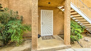 A building entrance with a white door, a concrete staircase, and surrounding greenery. - Pool & Hot Tub Access: Modern Palm Springs Condo (Palm Springs)