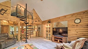 A cozy log cabin interior with a spiral staircase, a fireplace, a television, and a comfortable seating area. - 2 Decks & Fire Pit: Scenic Beech Mountain Retreat! (Banner Elk)