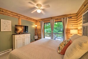 Een slaapkamer met een bed, een plafondventilator, een televisie, een dressoir en een raam met gordijnen.