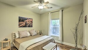 A bedroom with a bed, a bedside table, a nightstand, a window, a ceiling fan, and a wall-mounted picture. - East Austin Hideaway ~ 4 Mi to Ladybird Lake! (Austin)