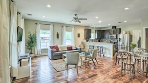 A spacious living area with a sofa, dining table, and chairs, a kitchen with modern appliances, and a ceiling fan. - East Austin Hideaway ~ 4 Mi to Ladybird Lake! (Austin)