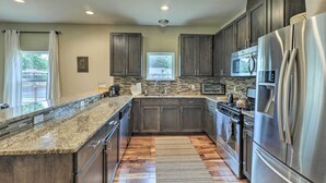 A modern kitchen with granite countertops, stainless steel appliances, and dark wood cabinets. - East Austin Hideaway ~ 4 Mi to Ladybird Lake! (Austin)