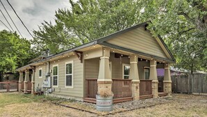 A single-story house with a porch, a wooden fence, and a barrel labeled "TARTER" in the yard. - East Austin Hideaway ~ 4 Mi to Ladybird Lake! (Austin)