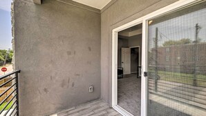 Un balcon doté d’un mur en béton, d’une rambarde en métal et d’une porte-fenêtre coulissante donnant sur une pièce intérieure.