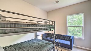 Une chambre avec un lit superposé, une fenêtre et une chaise bleue.