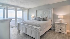 A bedroom with a large bed, a nightstand, and a view of the ocean. - Remodeled Redington Shores Gem on the Beach! (Redington Shores)