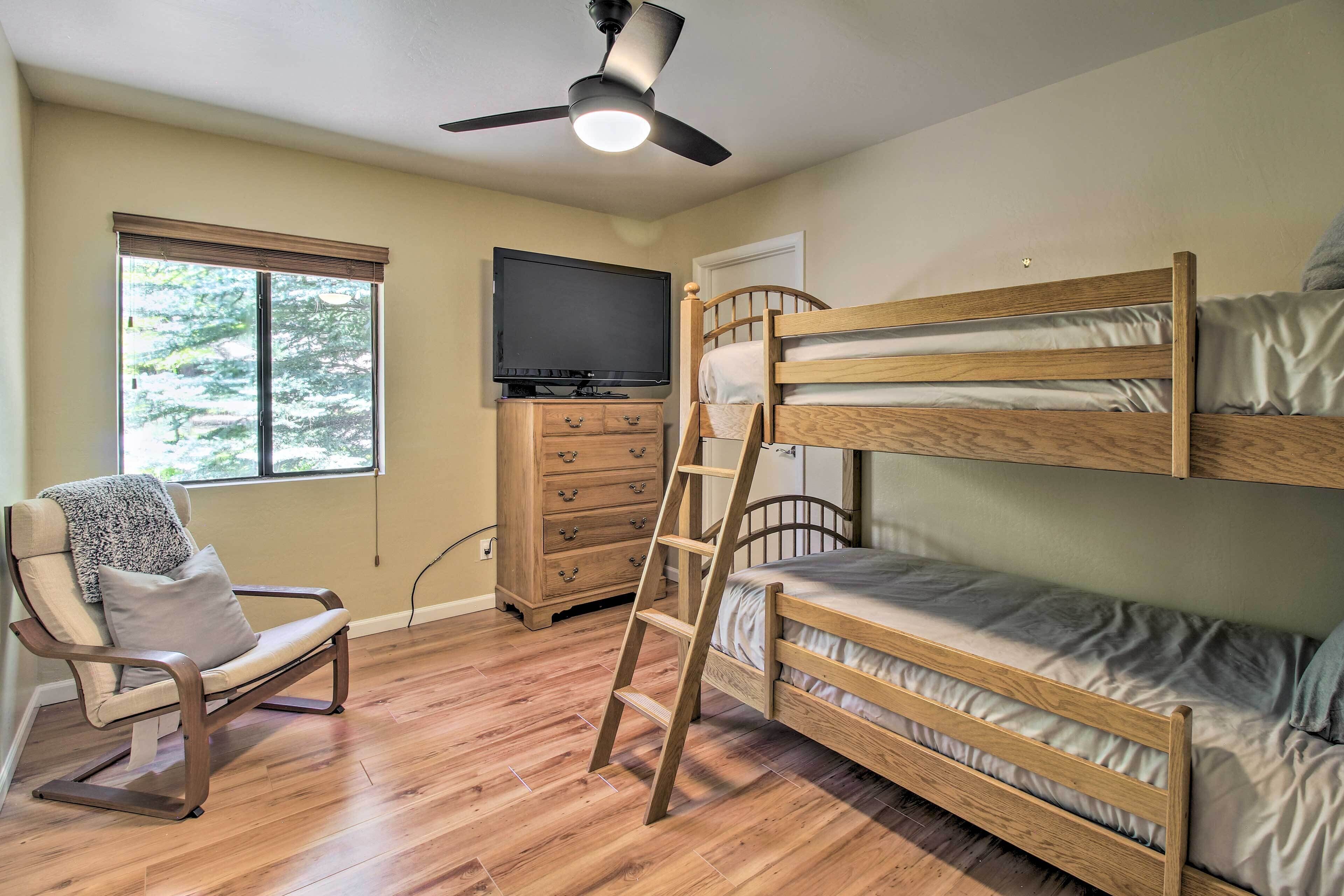 Une chambre avec un lit superposé, une chaise, un téléviseur et un ventilateur de plafond.