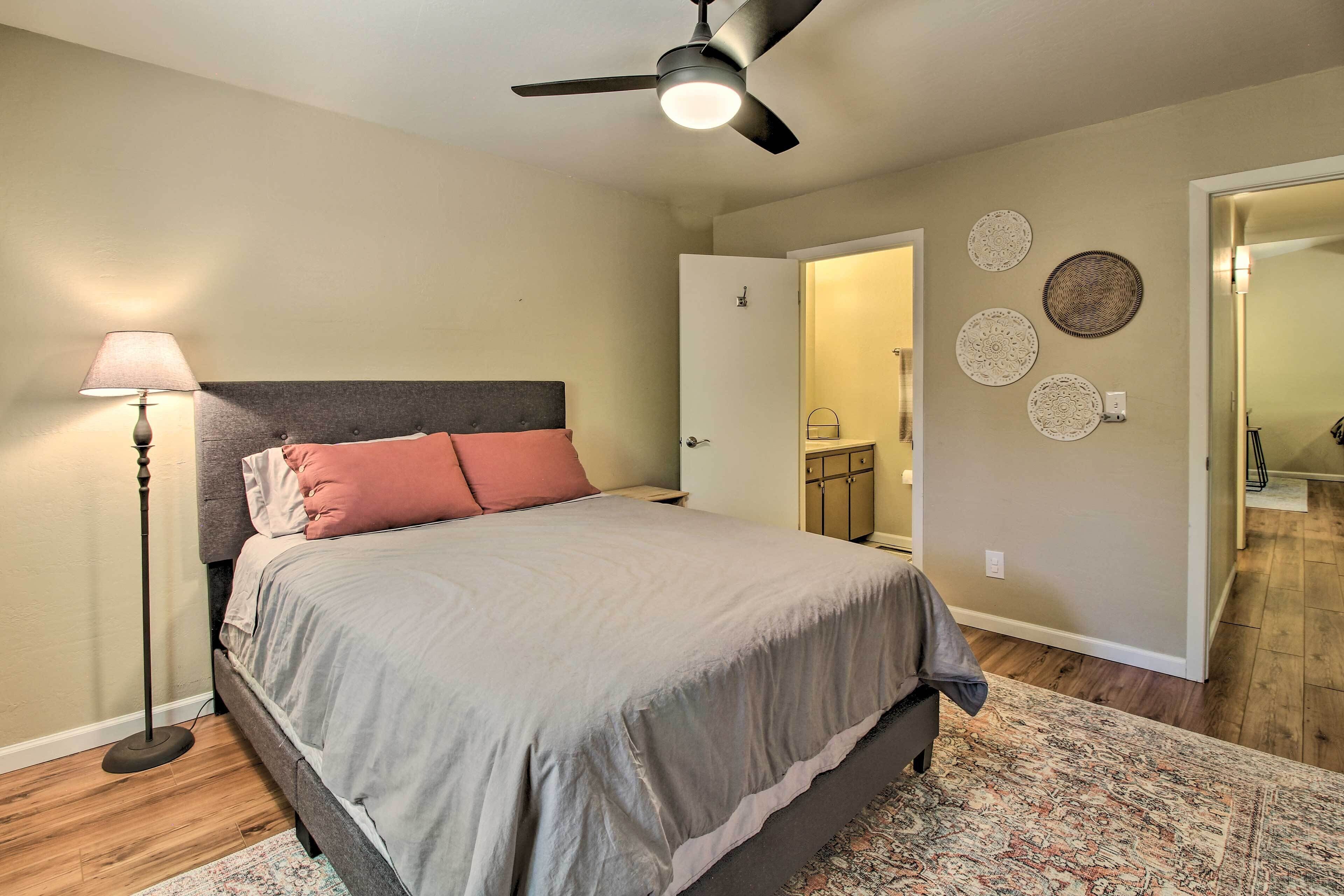 A bedroom with a bed, a floor lamp, a ceiling fan, and a rug.