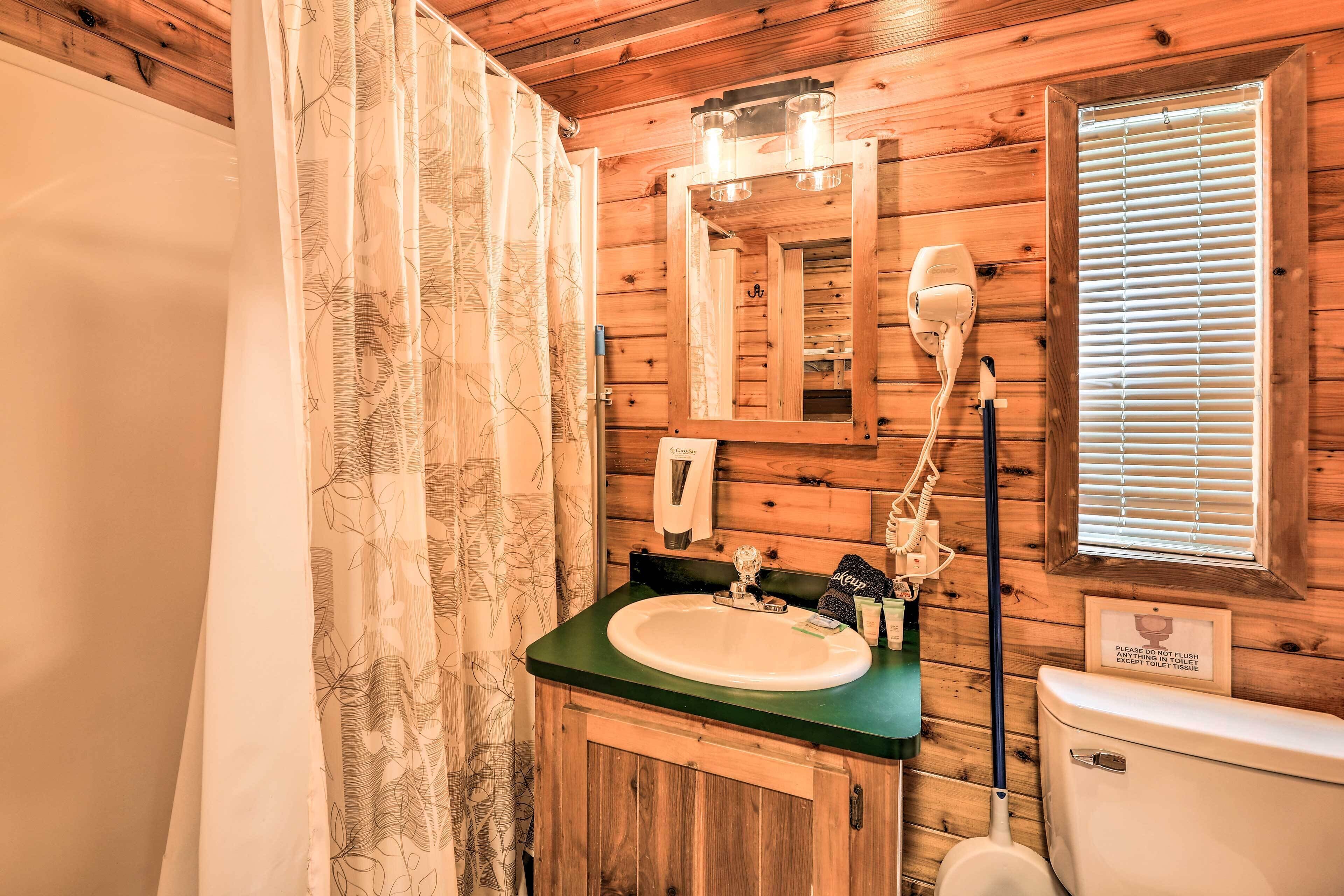 A wooden bathroom with a sink, mirror, and toilet.