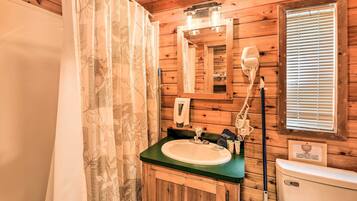 A wooden bathroom with a sink, mirror, and toilet.