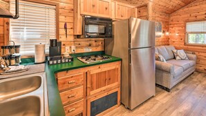 Una cocina compacta con armarios de madera, un refrigerador de acero inoxidable, un microondas y una estufa a gas.