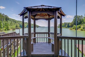 Un pabellón de madera con vistas a un lago y colinas boscosas.