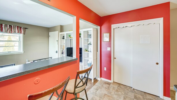 Eine Küche mit roter Akzentwand, einer weißen Tür und einem Fenster mit gestreifter Vorhang.