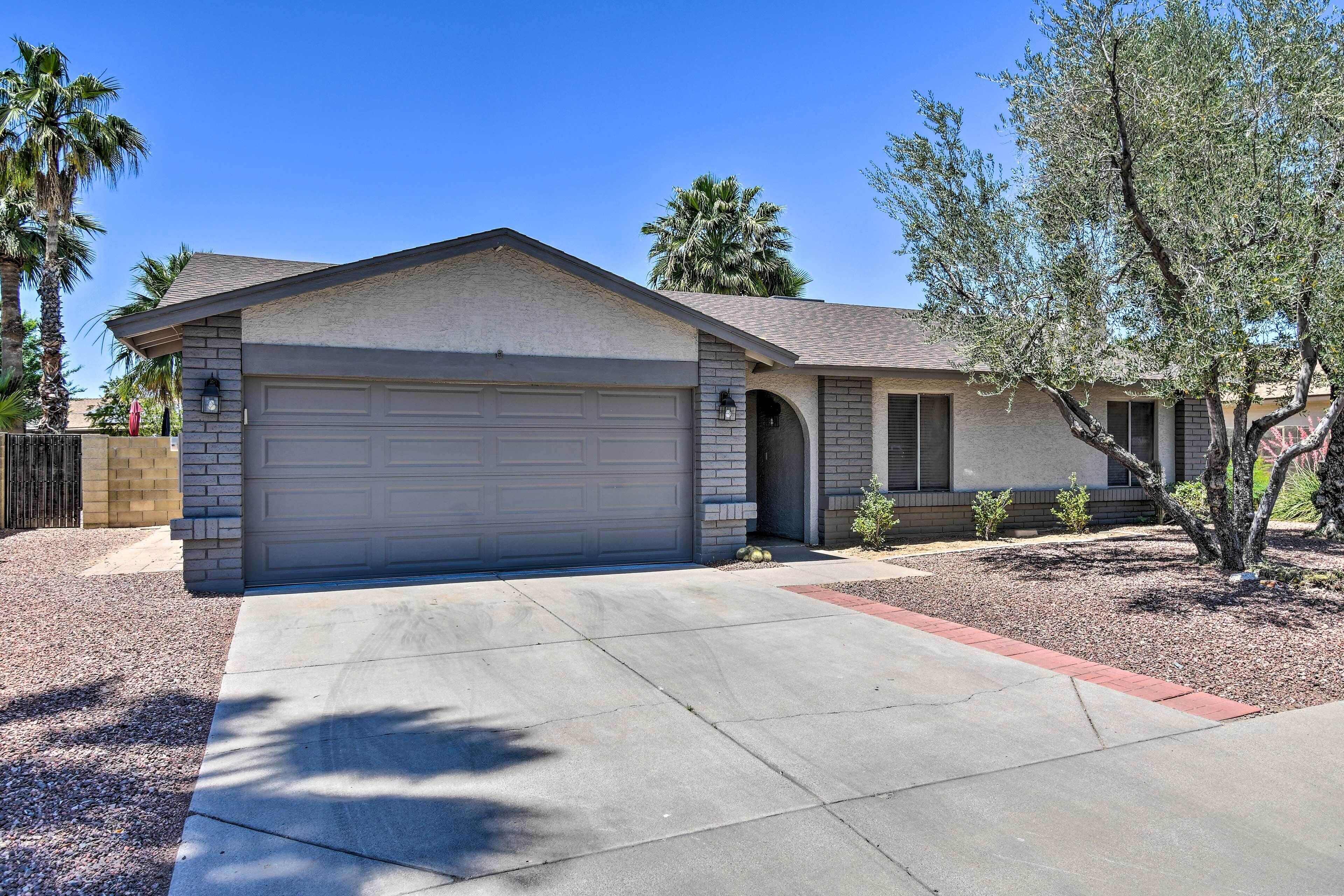 A single-story house with a garage, a small front yard, and a palm tree.