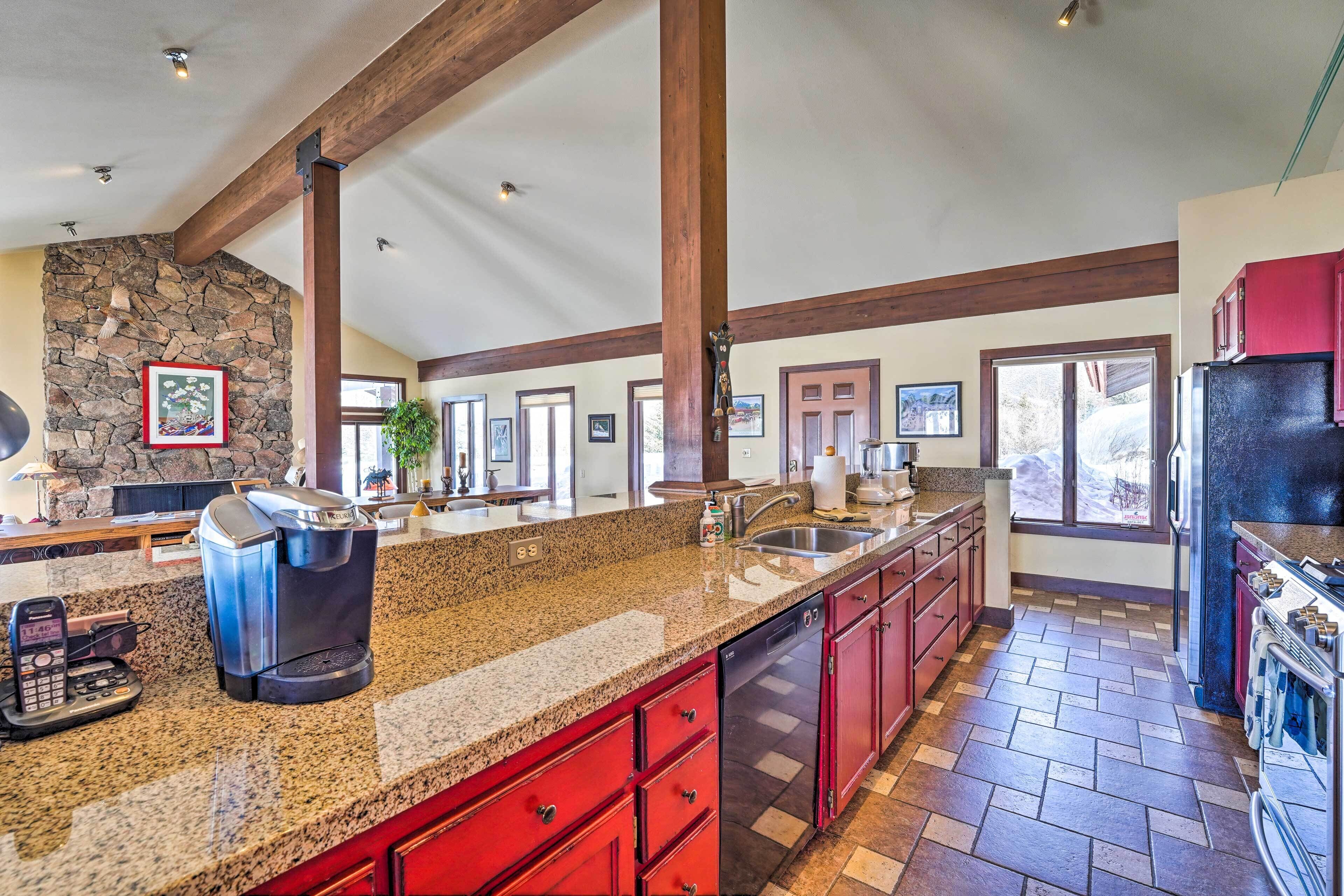 A spacious kitchen with granite countertops, red cabinets, and a stone accent wall.