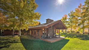 Un chalet rustique doté d’une cheminée en pierre, d’un porche abrité et d’une pelouse bien entretenue.