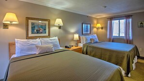 A hotel room with two beds, each with a green bedspread, white pillows, and a framed picture on the wall. There are two wall-mounted lamps, a window with curtains, and a nightstand with a phone. - Southern Maine Retreat < 2 Mi to Wells Beach! (Wells)
