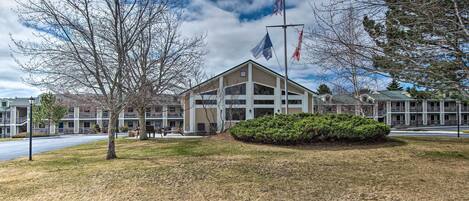 A building with a flagpole, a lawn, and a parking lot.