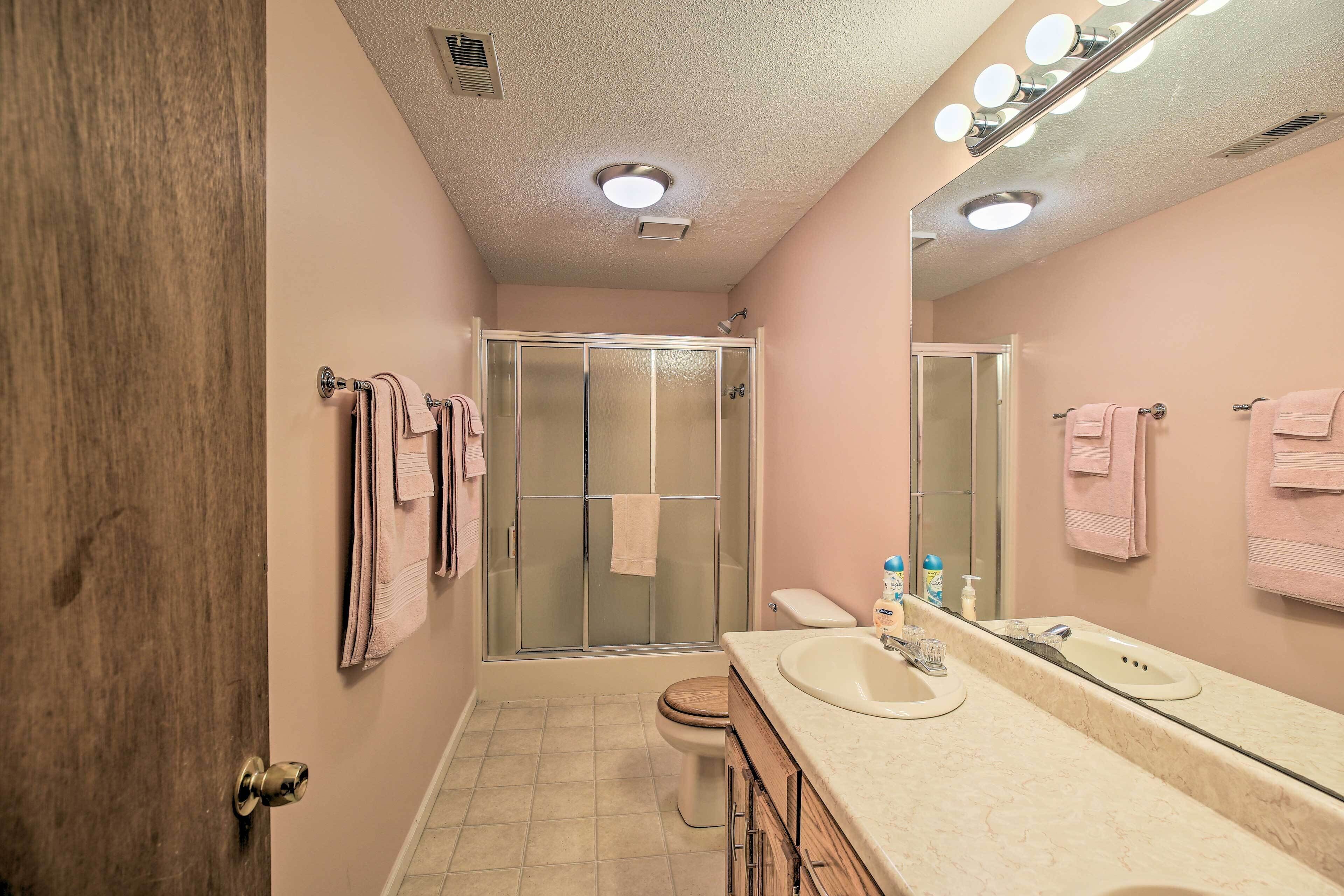 A bathroom with a shower, toilet, and vanity with a mirror.