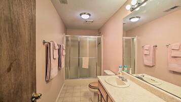 A bathroom with a shower, toilet, and vanity with a mirror.