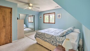 Quarto com cama, ventilador de teto, janela e porta.