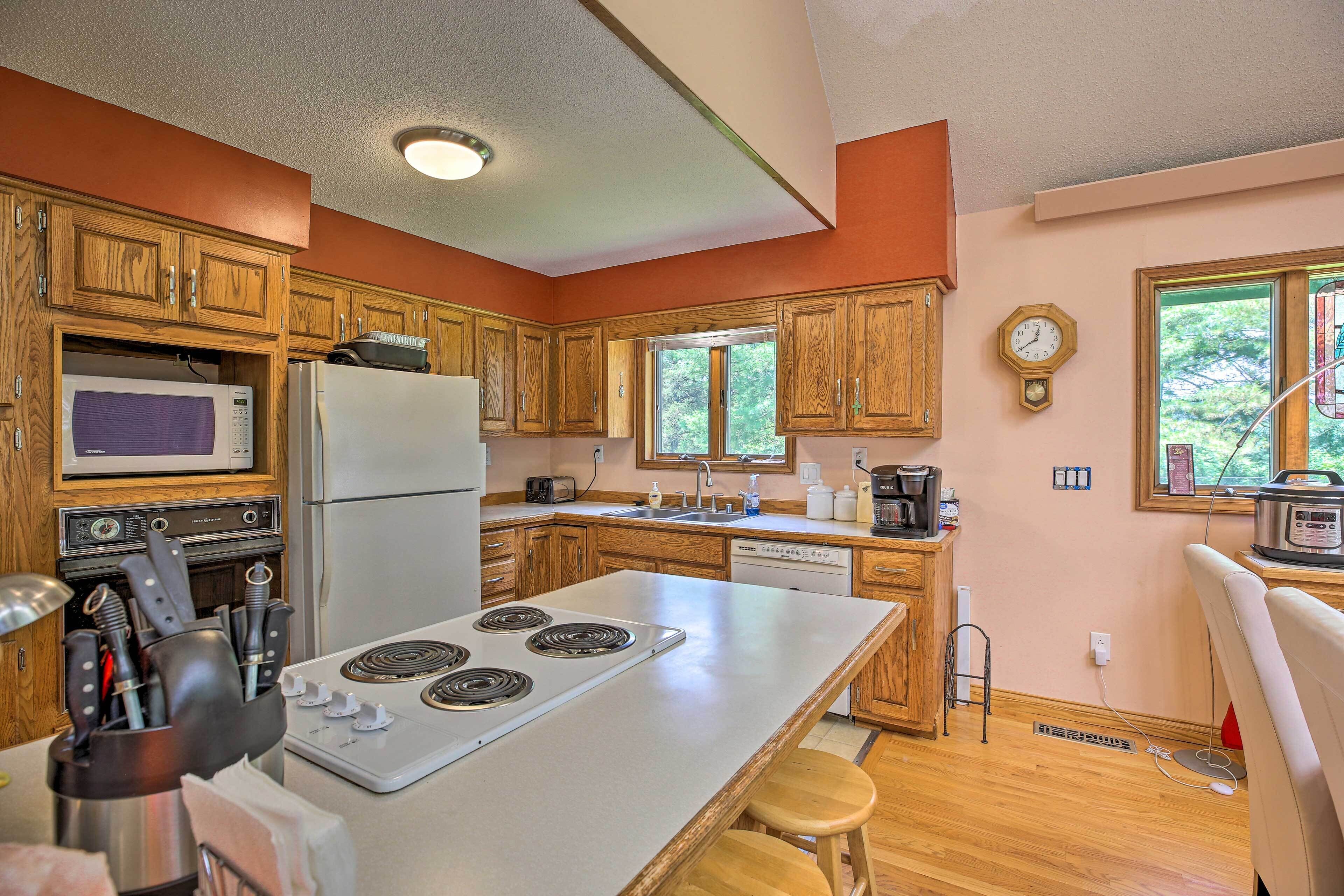 A kitchen with wooden cabinets, a microwave, stove, and a refrigerator.
